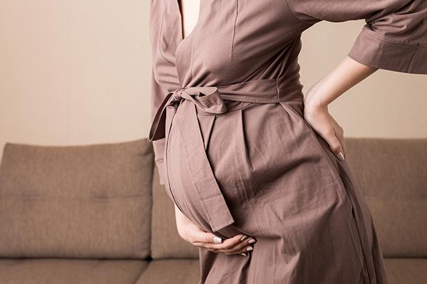 A pregnant woman supporting her baby bump