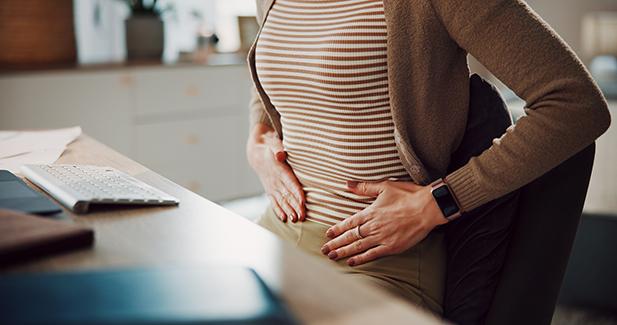 A woman with her hands on her belly in an indication of pain or discomfort