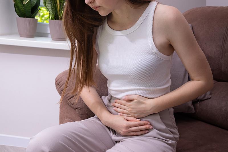 Female holding her lower belly, suffering from pelvic pain