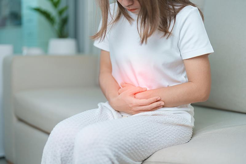 Woman holding her lower abdomen in pain, indicating discomfort related to gynaecological conditions